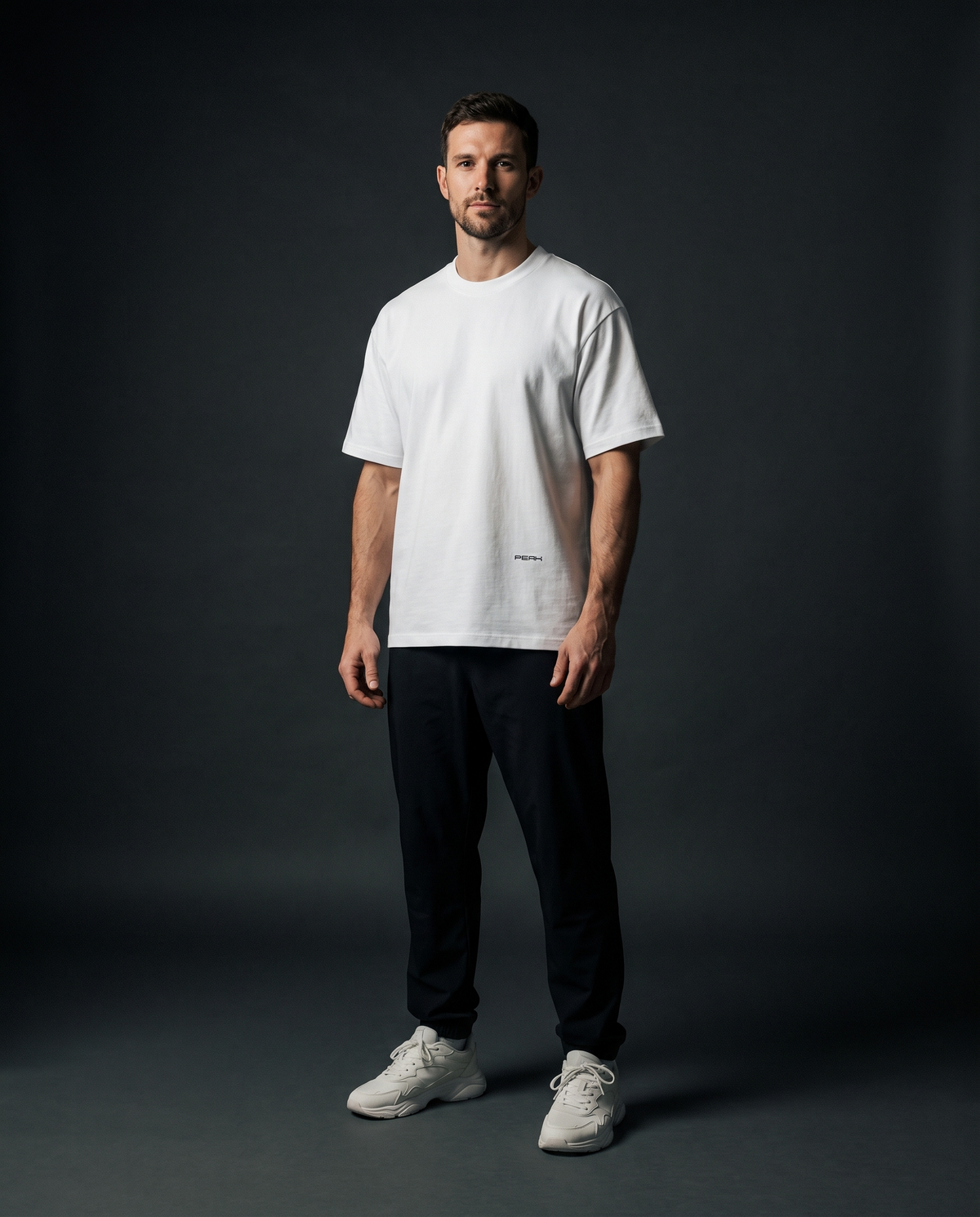 PEAK Hem Tee in White, worn in a dark studio