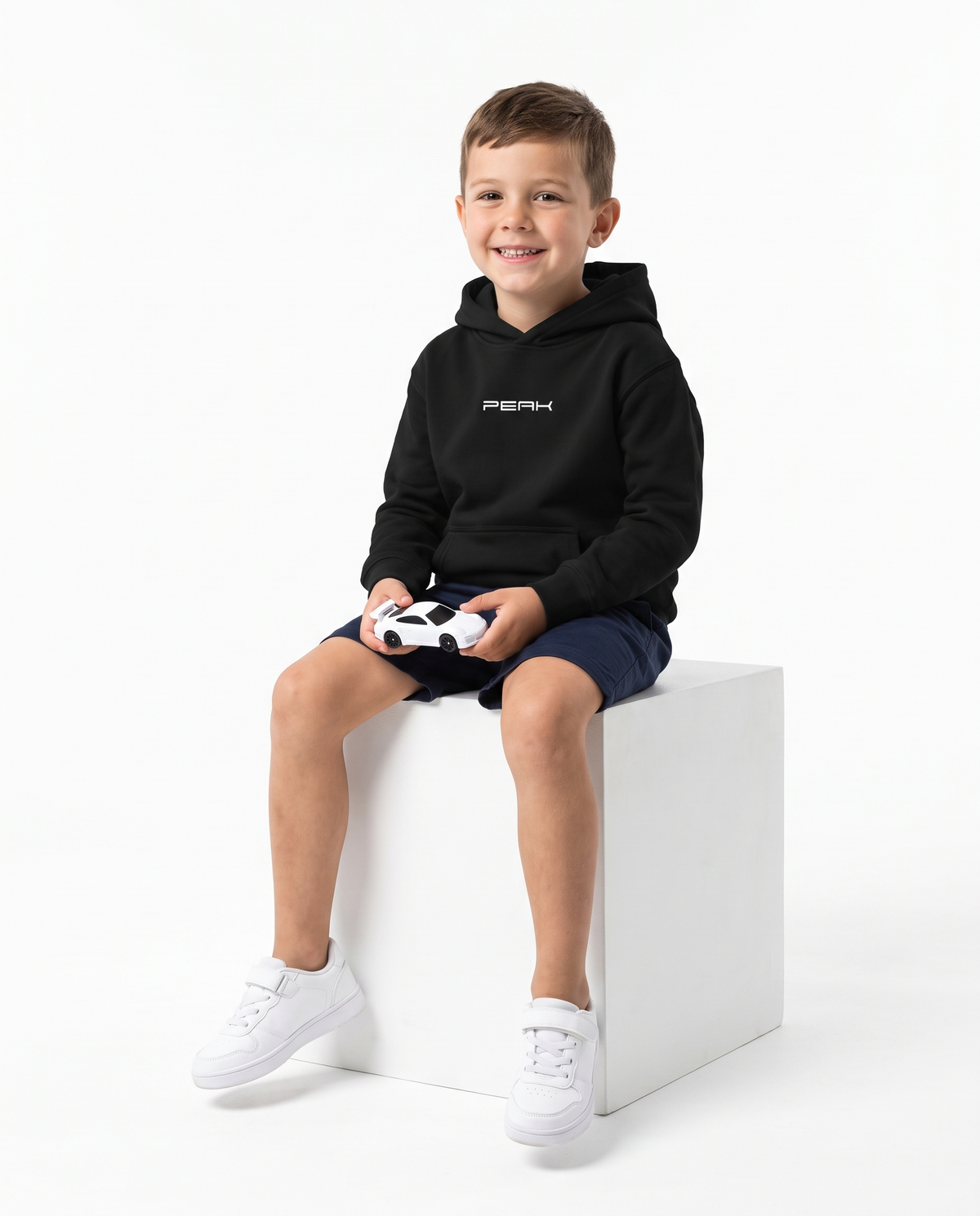 PEAK Kids Hoodie in Black, worn by a boy holding a toy race car