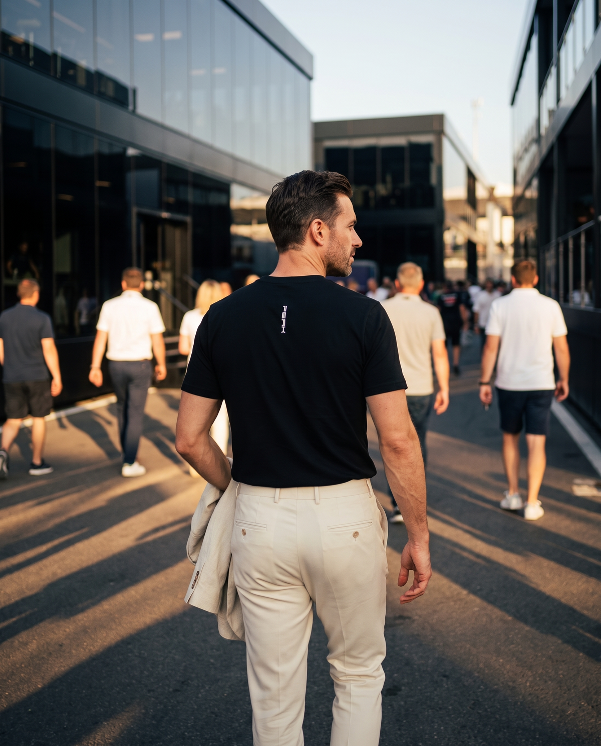 PEAK Tee, Chest & Spine Print, back view of the spine wordmark in a race paddock at golden hour
