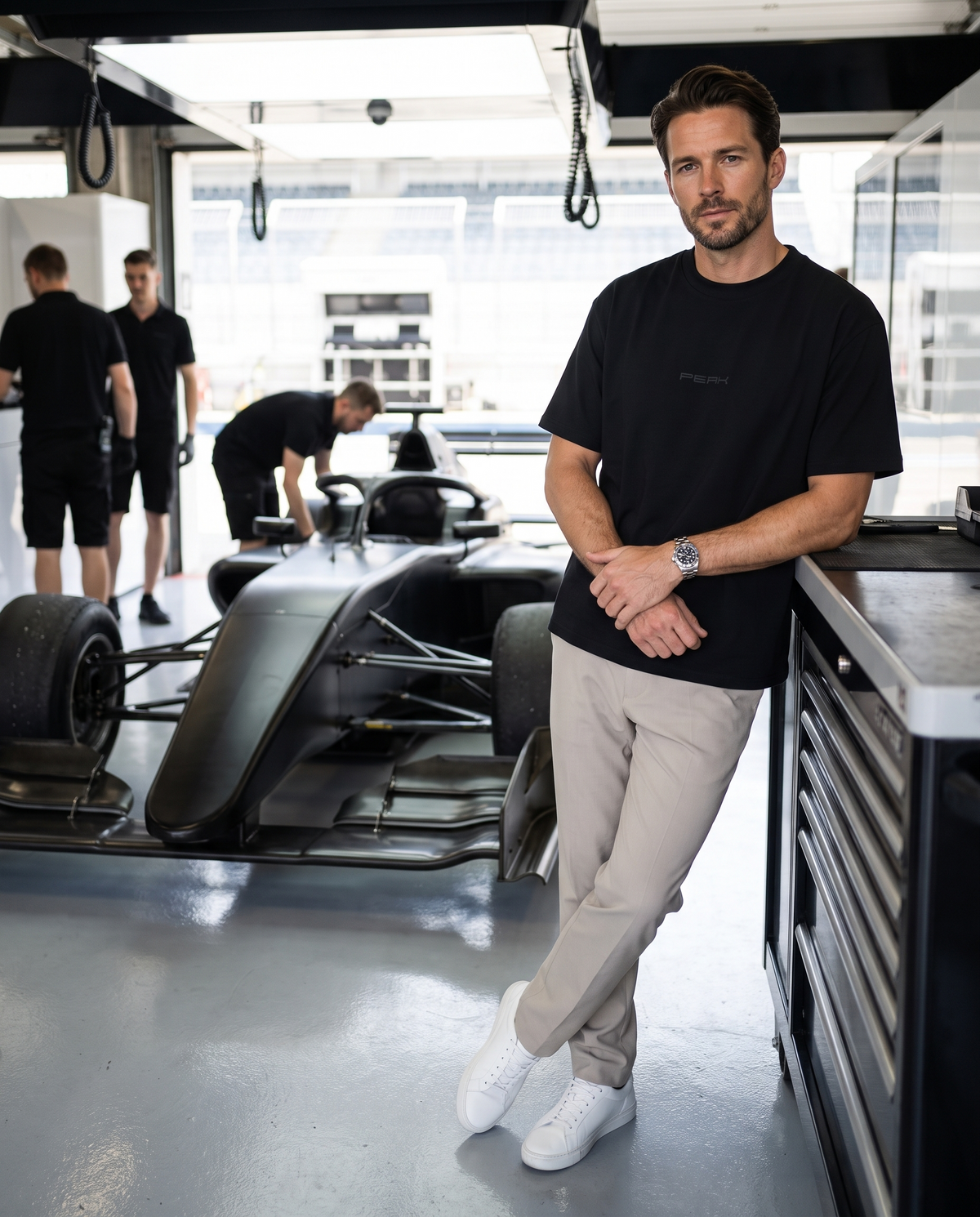 PEAK Tonal Tee in Black, worn in a race team pit garage