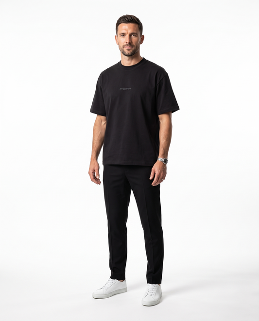 PEAK Tonal Tee in Black with a charcoal chest wordmark, worn by a man